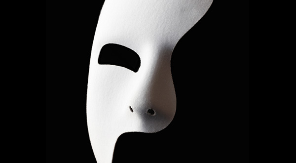 White mask showing one eye, nose, mouth with black background