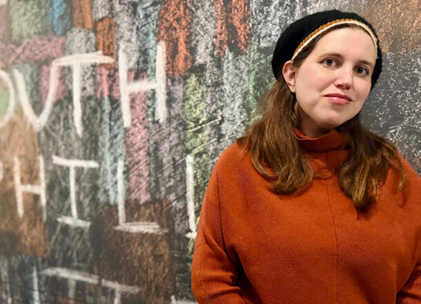 Woman wearing rust colored shirt against graffiti background featuring the words South Philly