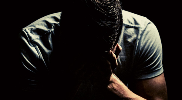 man hunched over with his face in his hands
