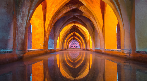 Glowing arched corridor reflected in still water, creating perfect symmetry.