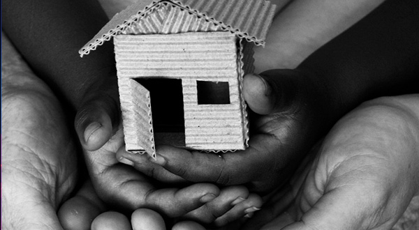 cardboard house being held by hands representing different generations